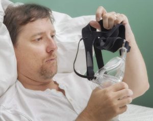 A man holding and examining his CPAP mask