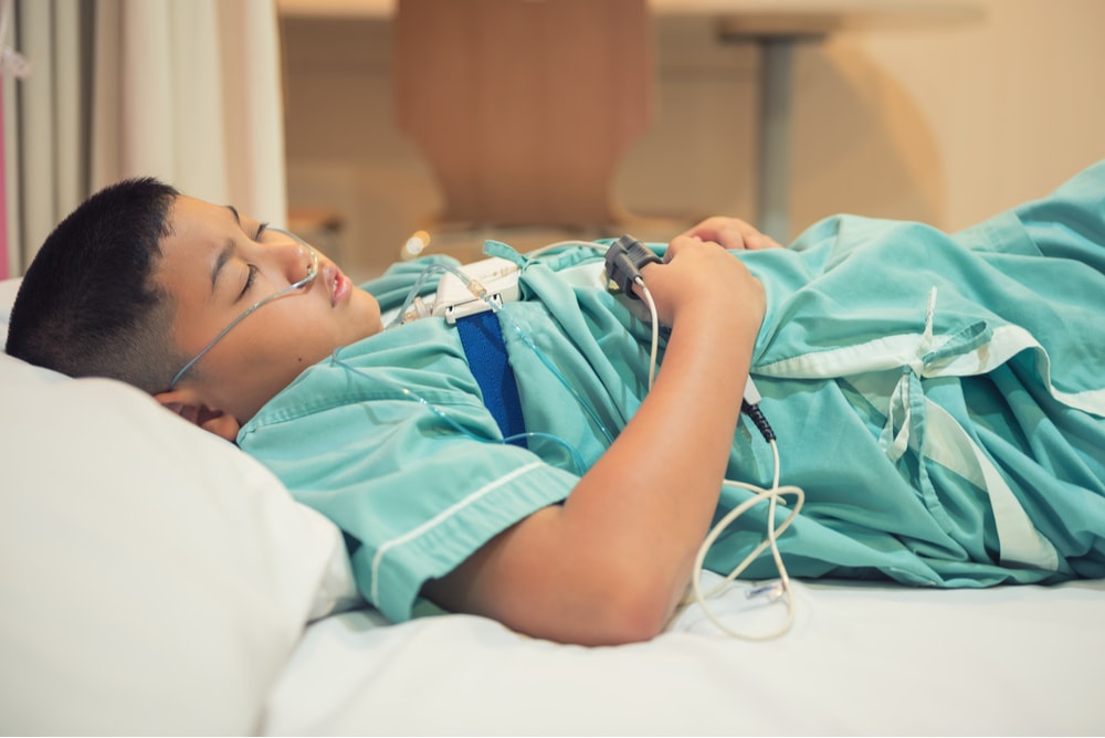 A boy sleeping peacefully, while attached to multiple cables, during a sleep study