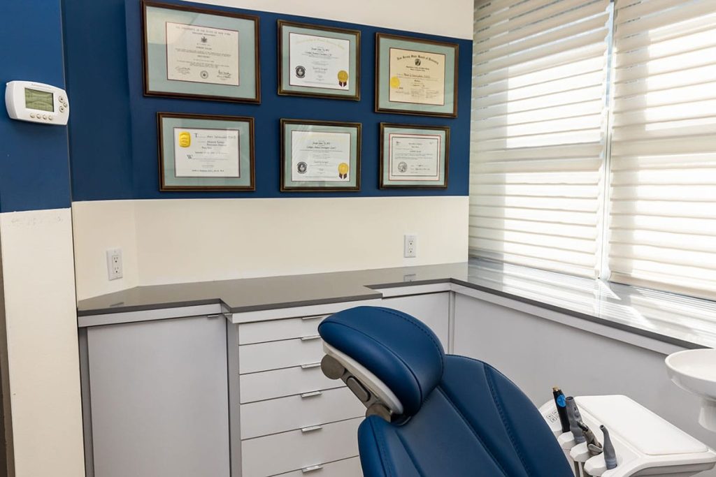 Dental exam room with blue wall and display of award certificates framed.