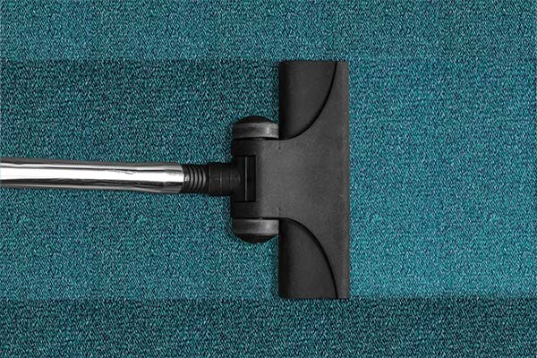 Carpet sweeper on blue carpet in clean dental office.