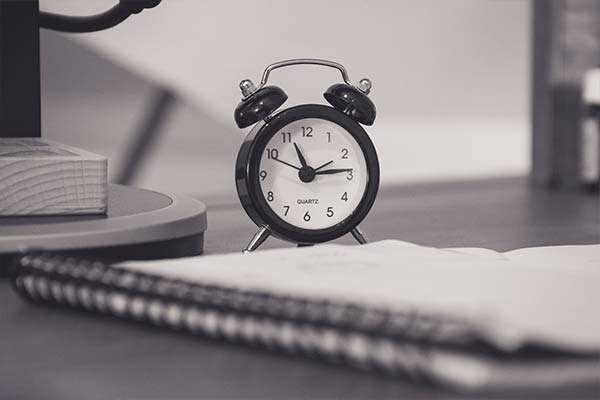 Close-up notebook with alarm clock on desktop in black and white.